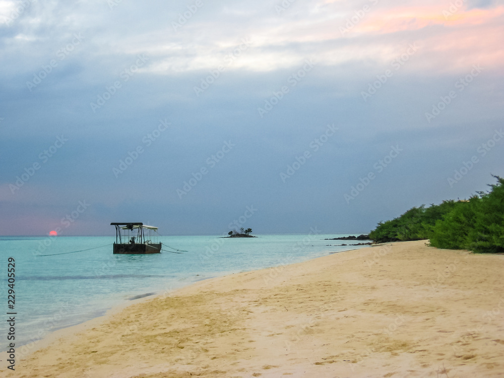 Maldives background. Sunset over the tropical sea and coral beach with colorful cloudy sky. Boats on the horizon. North Male Atoll Asdu, Indian Ocean. Maldives background. Sunset over the tropical sea and coral beach with colorful cloudy sky. Boats on the horizon. North Male Atoll Asdu, Indian Ocean.