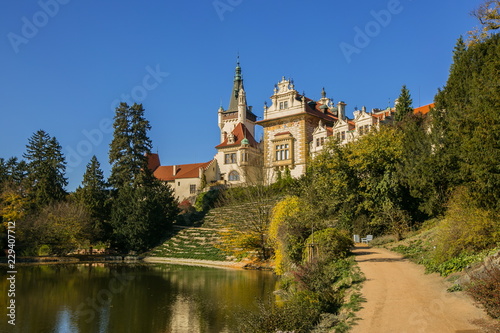 Famous romantic Pruhonice castle  Czech Republic  Europe  standing on hill in a park  sunny fall day  blue sky   colorful trees  reflection in water  foot path around lake  scenic landscape