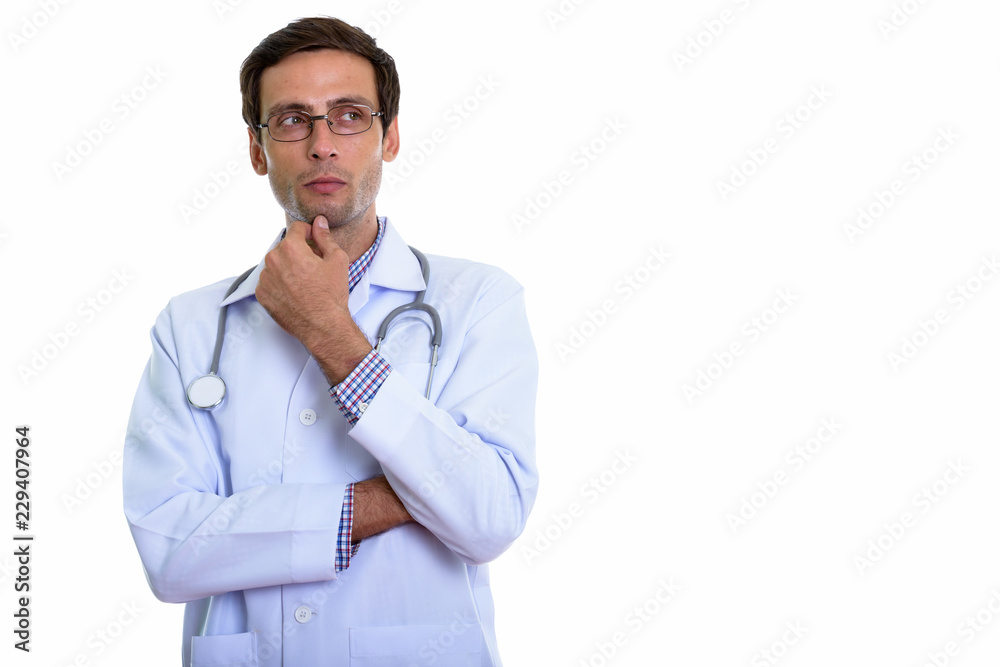Studio shot of young handsome man doctor thinking while looking Studio shot of young handsome man doctor thinking while looking
