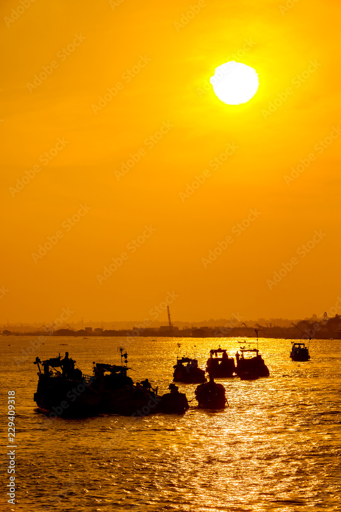 Silhouettes of small boats on Mekong river at sunset