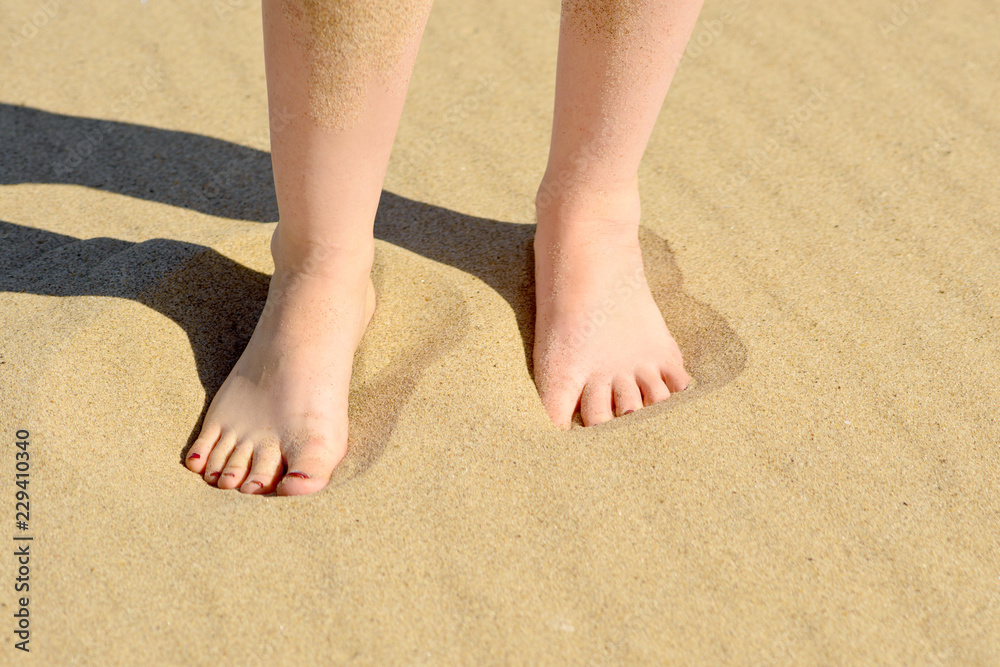 The feet of a woman walking on the sand leaving footprints The feet of a woman walking on the sand leaving footprints