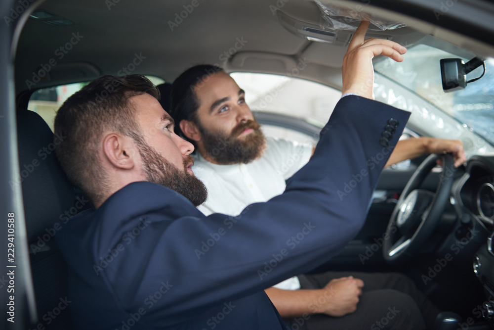Manager sitting with customer in car and showing details. Manager sitting with customer in car and showing details.