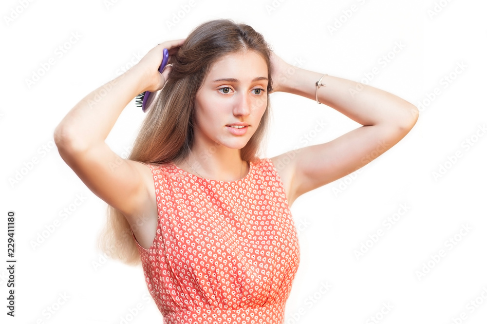 A girl with blond hair on a white background hairstyles herself and makes herself a hairdo