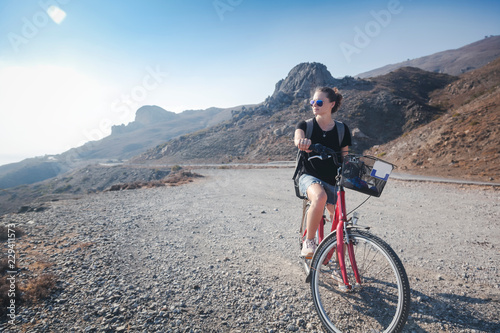 Young beautiful girl woman travels by bicycle on a mountain landscape on the beach in the sun, tourism and leisure concept, Greece, Kos