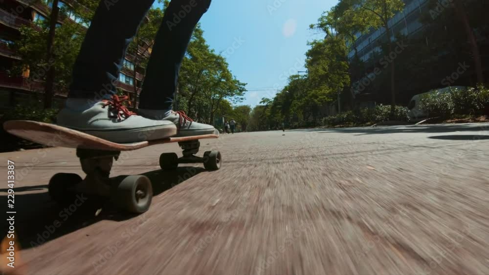 Low perspective shot of male feet in sneakers or skating shoes ride longboard and swerve on pavement. Cool extreme sport lifestyle or transportation mode for busy city life, always on move lifestyle