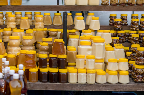 different honey in plastic jars stands on a wooden street counter