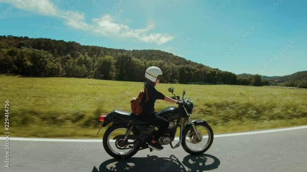 Happy, excited and adventurous young woman has fun best time of life rides motorcycle on warm summer day, travels on motorbike, feeling of freedom and happiness Happy, excited and adventurous young woman has fun best time of life rides motorcycle on warm summer day, travels on motorbike, feeling of freedom and happiness