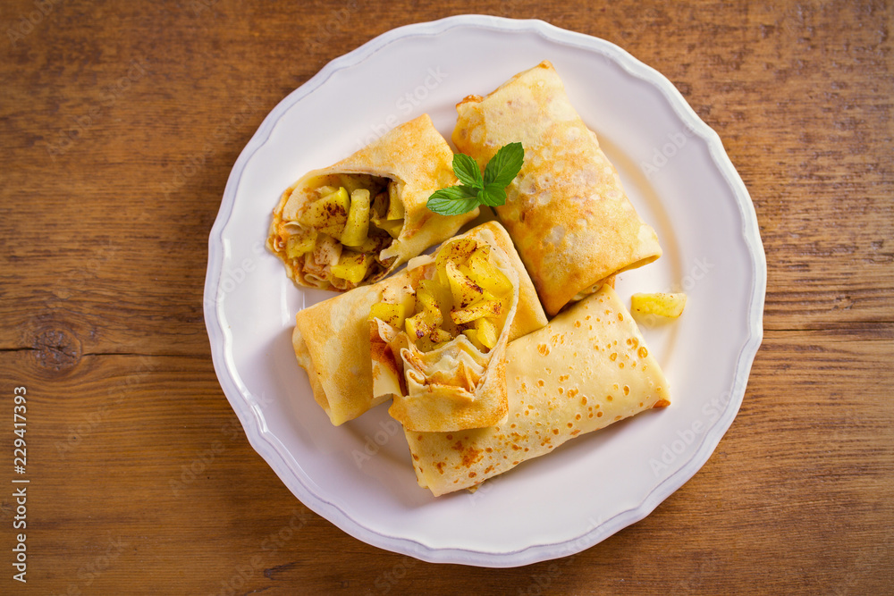 Delicious homemade crepes filled with apples and cinnamon. overhead, horizontal