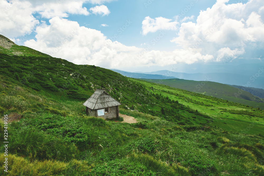 a small wooden hut on a slope in the mountains a small wooden hut on a slope in the mountains