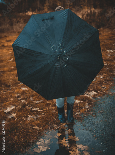 Woman hidden behind the umbrella in forest in autumn