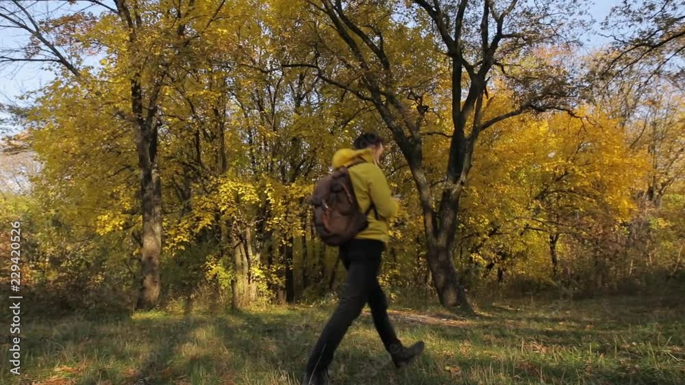 Man in yellow jacket walking with smartphone in the autumn forest Man in yellow jacket walking with smartphone in the autumn forest