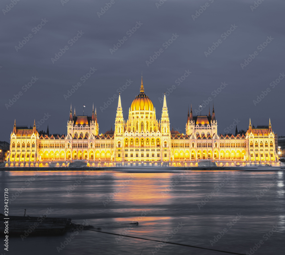 Obraz premium Parliament building in Budapest, Hungary. Building facade with reflection in water. Beautiful picture at sunset