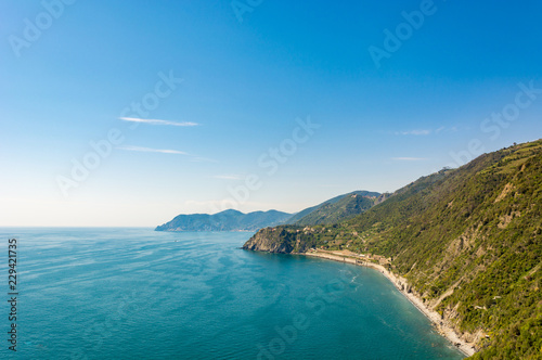 Ocean view with sun illuminating curvy coastline with hills. Cinque terre, Italy.