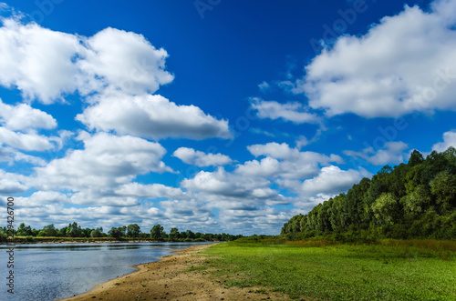 Landscape river on a background of green trees and blue sky with beautiful white clouds. Recreation on the nature. Fishing on the lake. Belarusian Polesie. Pripyat National Park