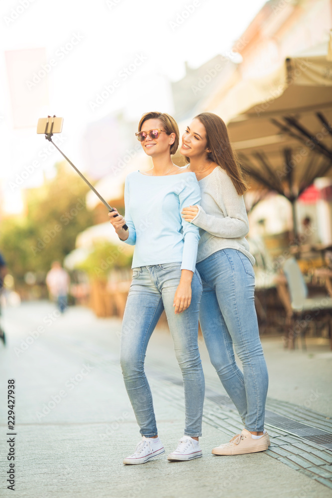 Two beautiful women taking a selfie using selfie stick