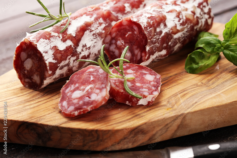 thinly sliced salami on a wooden texture on the background. thinly sliced salami on a wooden texture on the background.