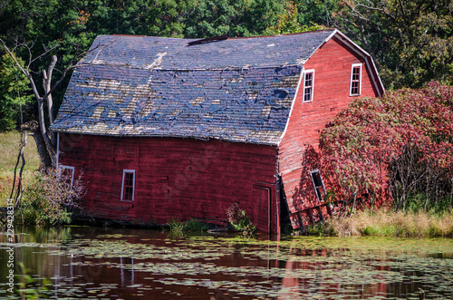 An abandoned red sinking barn sinks into a lake near Zimmerman, Minnesota photo
