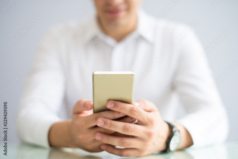 Close-up of businessman browsing internet on smartphone. Busy man sitting at table and reading online article on phone. Connection concept Close-up of businessman browsing internet on smartphone. Busy man sitting at table and reading online article on phone. Connection concept