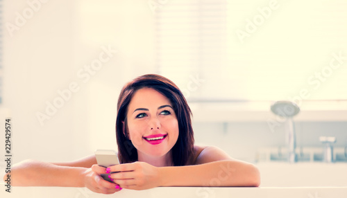 photo of the beautiful young woman having a bath and using her mobile phone