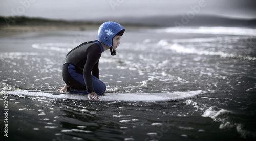 boy on surfboard heading out to the waves