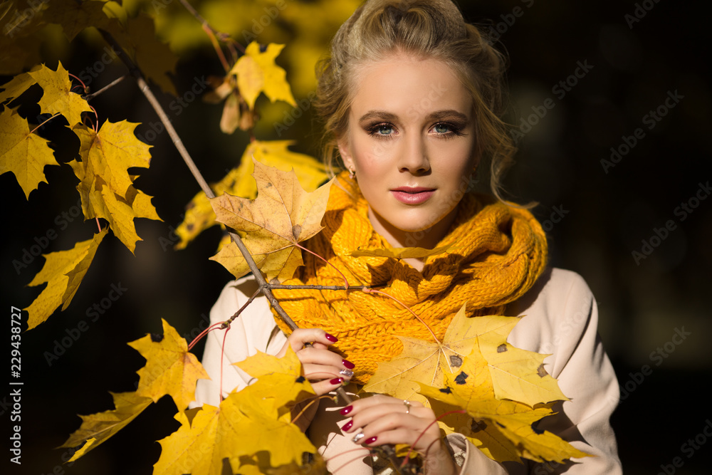 Pretty blonde girl in yellow autumn leaves
