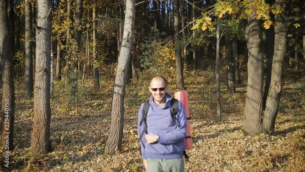 Man tourist with backpack behind, walking through the woods Man tourist with backpack behind, walking through the woods