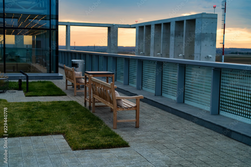 Modern rooftop patio with wooden benches in evening