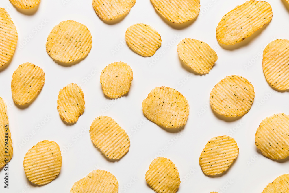 Crispy potatoes chips isolated on white background. Food background. Potato chips lying at a distance from each other on a white table. Crispy potatoes chips isolated on white background. Food background. Potato chips lying at a distance from each other on a white table.