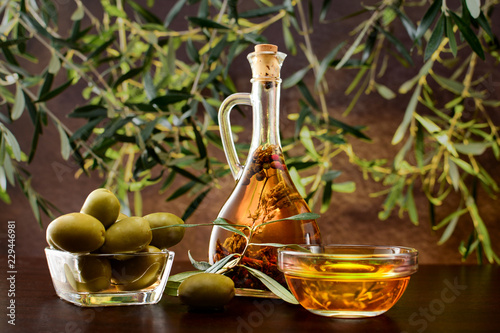 Tradition Crete flavored olive oil with spieces rosemary and pepper in local vial, with olives, and olive leafs on wooden background.