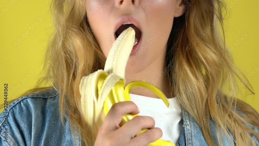 Beautiful girl eating banana enjoying flavor of tropical fruit, slow-motion