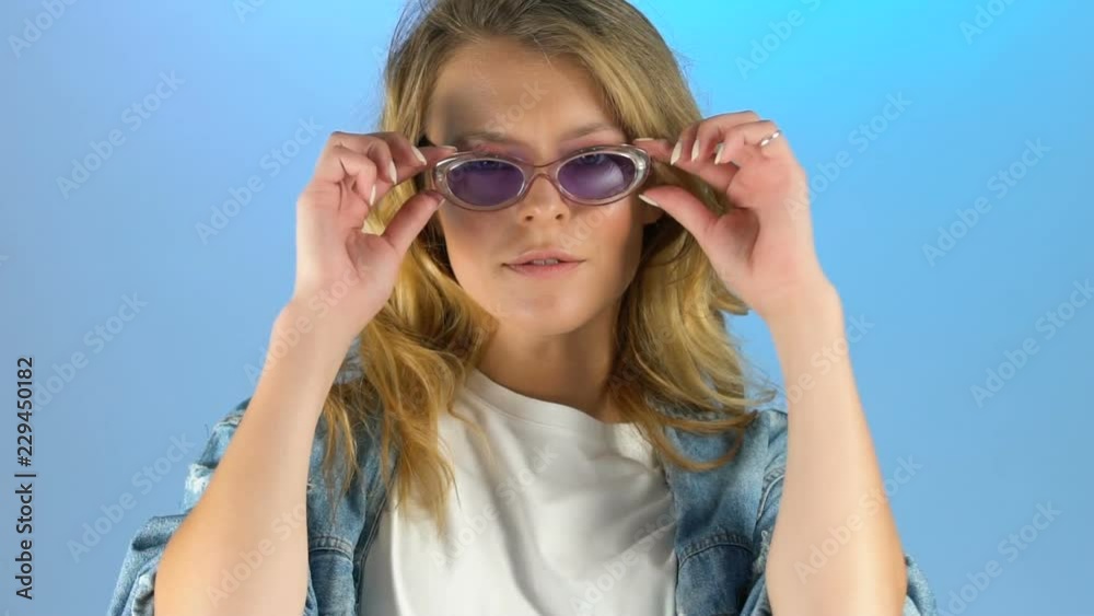 Pretty lady taking off sunglasses and looking into camera with piercing glance Pretty lady taking off sunglasses and looking into camera with piercing glance