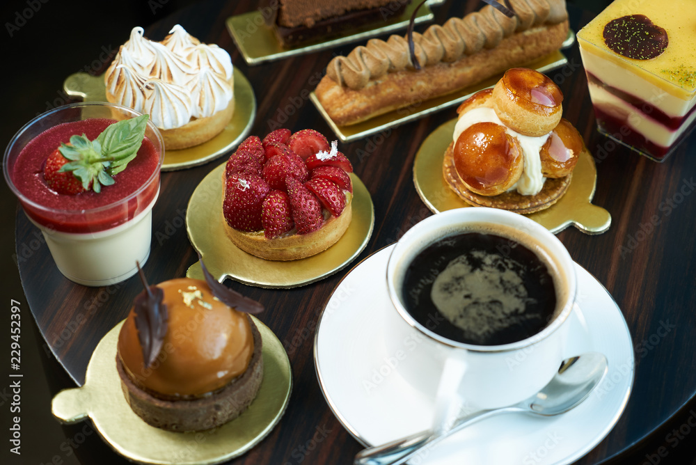 Breakfast time with cup of hot coffee and pieces of cream cake with strawberries and raspberries, sweets dessert breakfast snacks, close-up. Berry cupcakes dessert on wooden table background, top view Breakfast time with cup of hot coffee and pieces of cream cake with strawberries and raspberries, sweets dessert breakfast snacks, close-up. Berry cupcakes dessert on wooden table background, top view