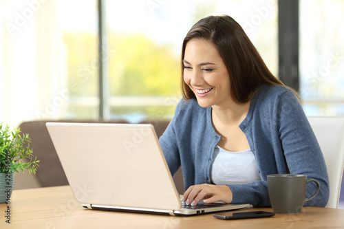 Woman writing in a laptop on a desk at home © Antonioguillem