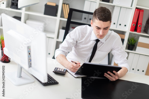 A young man sitting at a computer Desk in the office and working with documents.