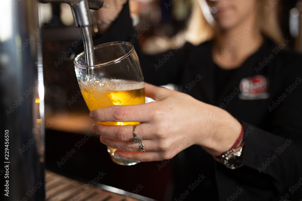 Girl in a bar serving a glass of beer for a customer 
