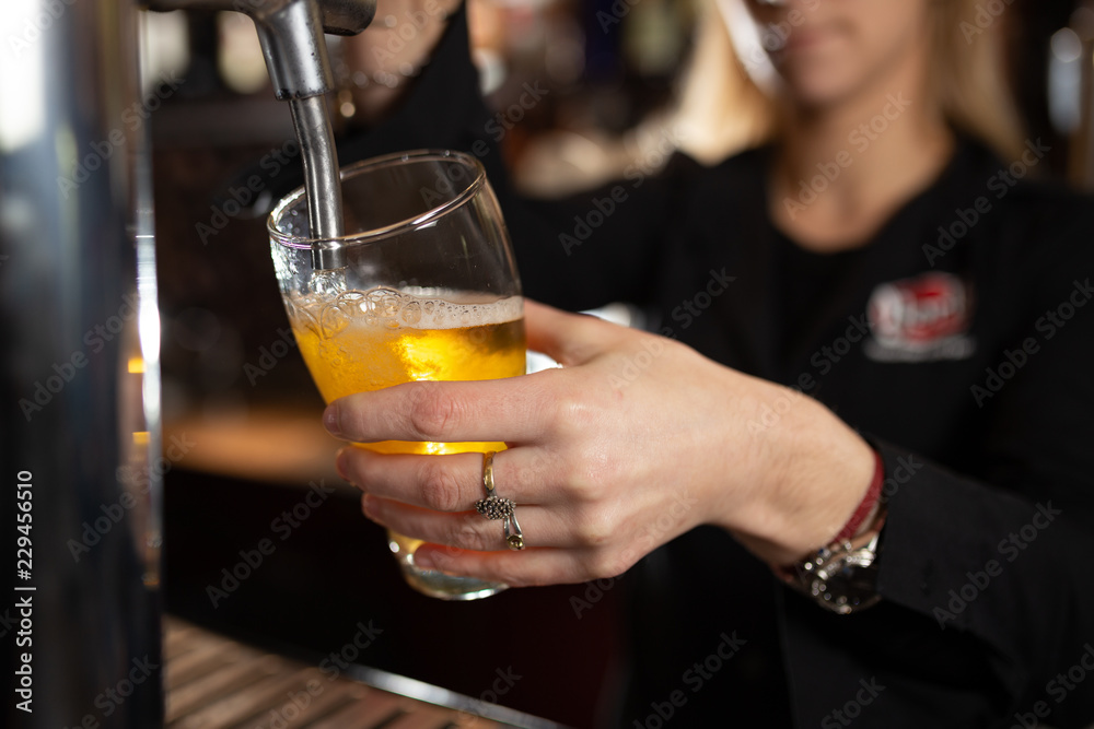 Girl in a bar serving a glass of beer for a customer Girl in a bar serving a glass of beer for a customer