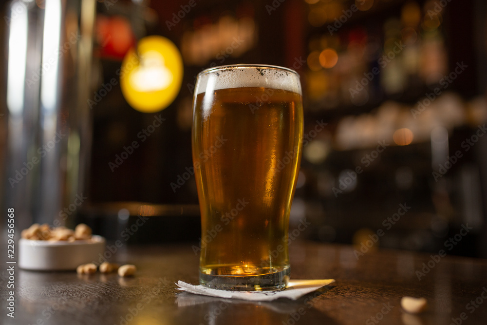 Enjoy a pint glass of golden beer with snacks in a bar Enjoy a pint glass of golden beer with snacks in a bar