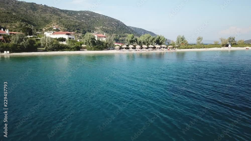 Aerial view, grazing flight on the transparent sea approaching a withe sand beach Aerial view, grazing flight on the transparent sea approaching a withe sand beach