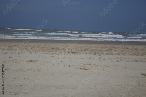 Beautiful beach with clear blue sky and white sand with some waves coming from the ocean