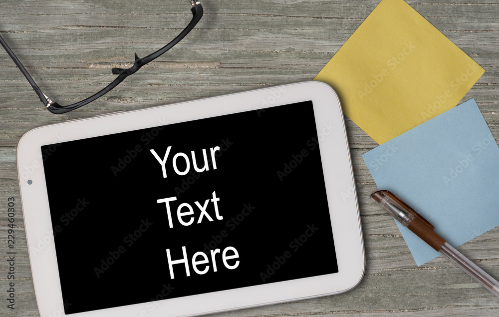 PURE BLACK SCREEN TABLET ON WOODEN TABLE WITH A PAIR OF GLASSES, PAPER NOTES AND A PEN (FOR ADD YOUR TEXT ON THE SCREEN)