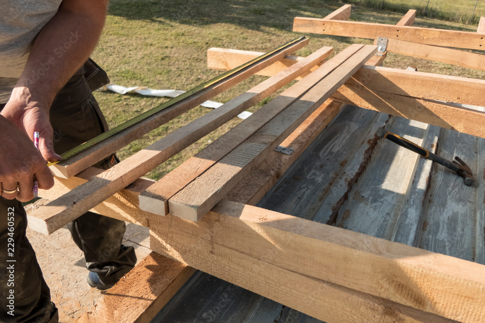 Roof construction building. Man measuring elements with tape measure or scoop.