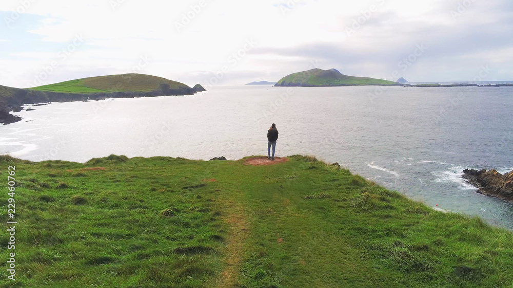 Girl stands on the edge of a cliff at the west coast of Ireland Girl stands on the edge of a cliff at the west coast of Ireland