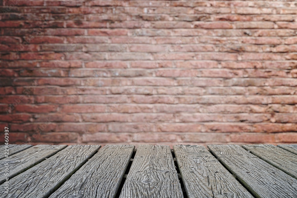 EMPTY WOOD DECK WITH BLUR BRICK WALL BACKGROUND IN VIGNETTE EFFECT (FOR PRODUCT DISPLAY MONTAGE).