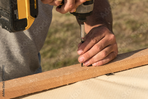 Roof construction building. Man using electrical scredriver to attach construction elements. photo