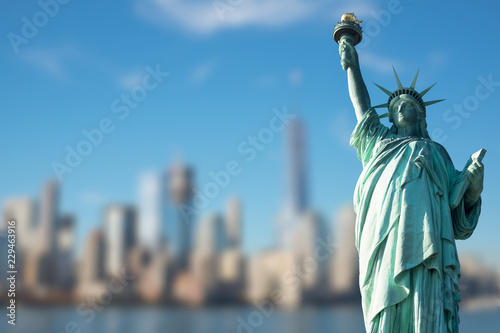 STATUE OF LIBERTY WITH BLUR BACKGROUND OF SKYSCRAPERS IN MANHATTAN, NEW YORK, USA