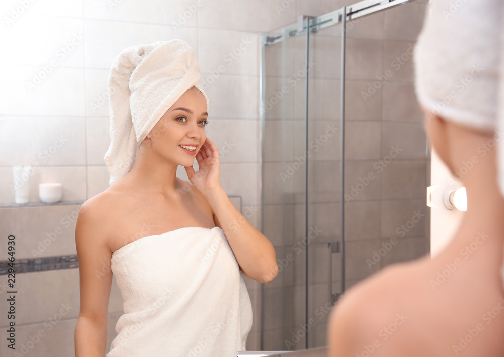 Beautiful woman with clean towels near mirror in bathroom Beautiful woman with clean towels near mirror in bathroom