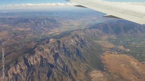 POV-Aircraft wing flying over rugged mountains and northern cities of Utah's Wasatch Front as aircraft descends for landing at Salt Lake City