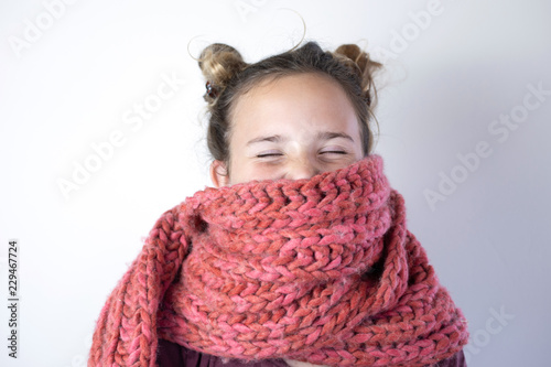Young girl bundled with pink knitted scarf.