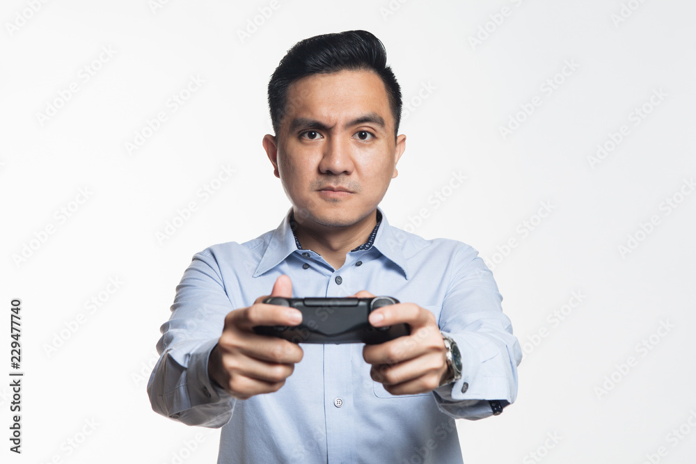 Asian man in work cloth playing console game Asian man in work cloth playing console game