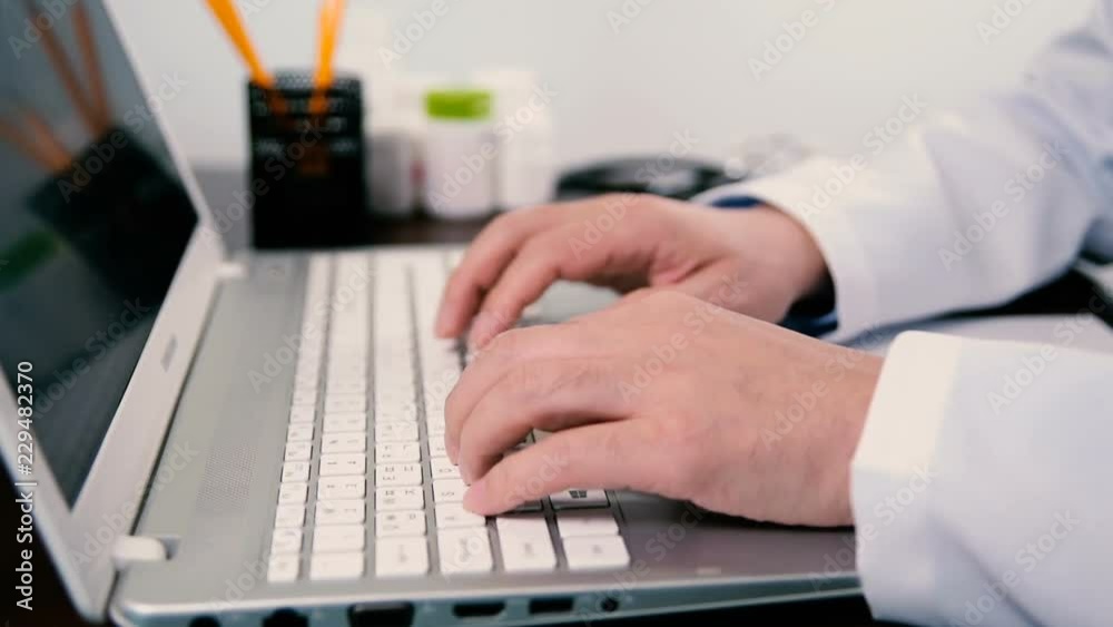 Close-up of a male doctor using a computer keyboard. Close-up of a male doctor using a computer keyboard.